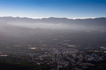 Panoramic view on the valley of the city Los Llanos. Clouds climb over a mountain in the background.