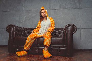 Pajamas in the form of a kangaroo. emotional portrait of a student on the background leather sofa....