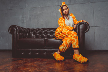 Pajamas in the form of a kangaroo. emotional portrait of a student on the background leather sofa....