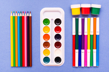 Obraz premium Accessories for drawing - pencils, felt-tip pens, watercolor and gouache blue background. Top View.
