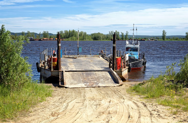 River barge with ramp and boat on the pier near the shore waiting for loading