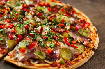 sliced Pizza with Mozzarella cheese, mushrooms, salami, bacon, Tomatoes, pepper, Spices and Fresh Basil. Italian pizza on wooden background.