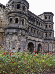 Obraz premium Porta Nigra - a Roman city gate in Trier - the oldest city in Germany with a rose alley in front, view from the main street