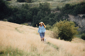 girl in a hat playing with a dog in the field at sunset sun