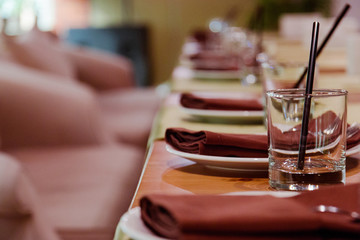 elegant table setting at a banquet for several people, brown napkins cups straws