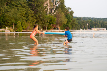 Children playing tug of war with pool noodle in Lake Michigan