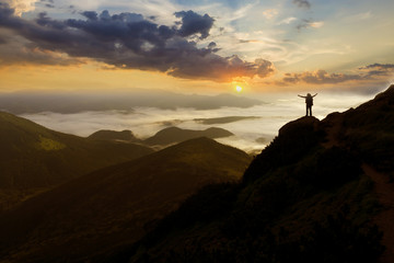 Wide mountain panorama. Small silhouette of tourist with backpack on rocky mountain slope with...