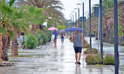 Fototapeta na wymiar un uomo con omrello passeggia su un lungomare mentre piove
