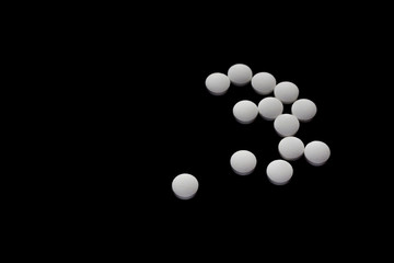 Close up pills isolated on black background. Treatment, narcomania.
