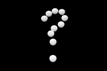 Close up question of pills isolated on black background. Medical dilemma. Narcomania, treatment.