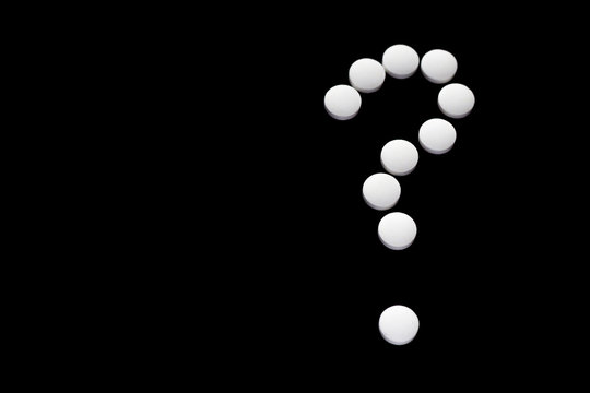 Close up question of pills isolated on black background. Medical dilemma. Narcomania, treatment.