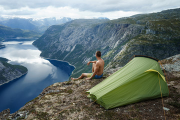Fototapeta premium Norwegian fjord landscape with camping tent and young traveller. concept of travel and freedom