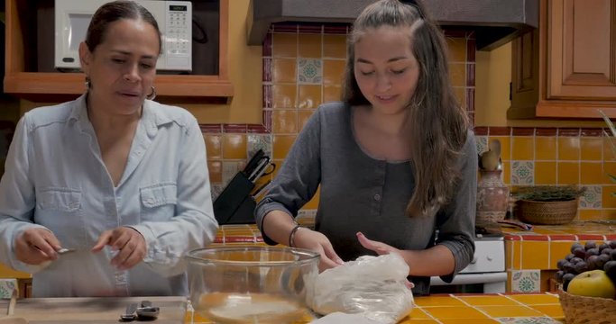 Attractive mother and beautiful daughter working together baking and cooking