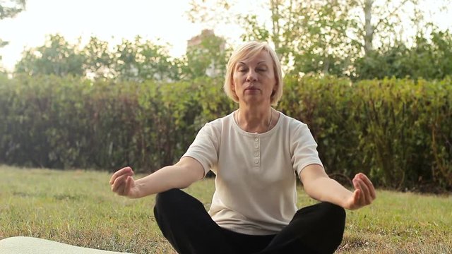 Best ager women practicing yoga and tai chi outdoors. Elderly woman meditating