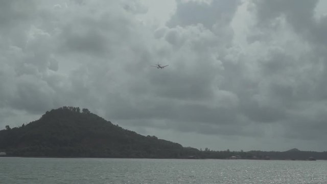 Airplane flying in the cloudy sky over island