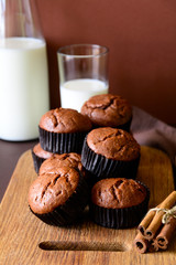 Homemade chocolate muffins (brownies) with cinnamon and milk on brown paper background