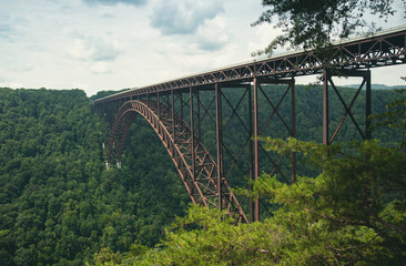 A view of the steel metal arch bridge over the New River Gorge in Fayetteville, West Virginia.  The bridge is the longest steel span in the western hemisphere.  Repeating lines.  Horizontal image.