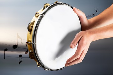 Female hands Playing the tambourine on background - obrazy, fototapety, plakaty