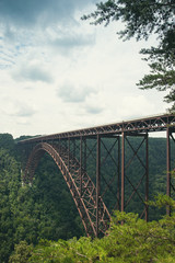 Obraz premium A view of the steel metal arch bridge over the New River Gorge in Fayetteville, West Virginia. The bridge is the longest steel span in the western hemisphere. Repeating lines. Vertical image.