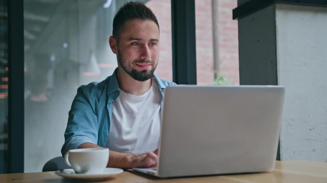 A young man sitting and using a computer indoors. Medium shot.