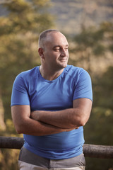 one young overweight man, 30-35 years, looking sideways, arms crossed, outdoors portrait, upper body shot.