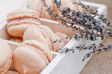 Beautiful macaroons in a light wooden box and sprigs of lavender