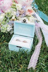 Box of tiffany color with rings and a beautiful wedding bouquet on the grass