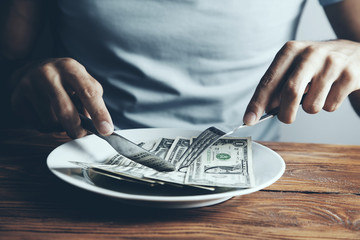 Hands cut money on plate reduce funds concept