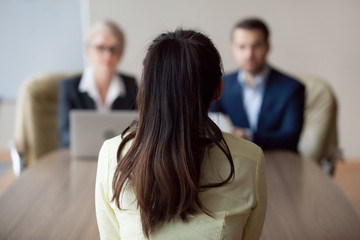 Businesswoman and businessman HR manager interviewing woman. Candidate female sitting her back to...