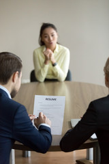 Businesswoman and businessman HR managers interviewing asian woman candidate. Boss holding paper,...