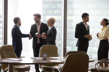 Multiracial, business people talking in break, drink coffee, standing near window. Asian and...