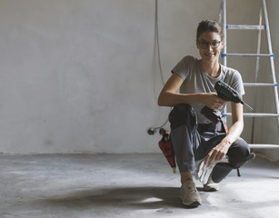 Professional repairwoman posing and holding a drill