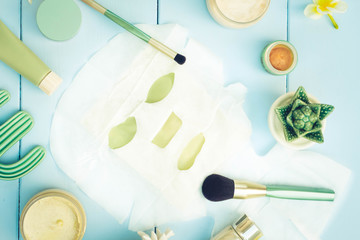 Beauty background with facial cosmetic products and sheet mask on blue wooden background. Beauty spa and wellness concept, retro toned