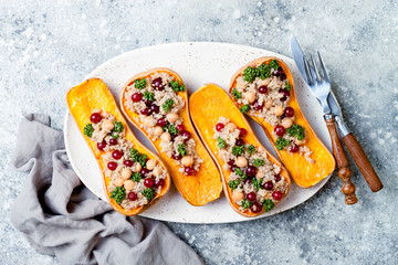 Stuffed butternut squash with chickpeas, cranberries, quinoa cooked in nutmeg, cloves, cinnamon. Thanksgiving dinner recipe. Vegan healthy seasonal fall or autumn food - obrazy, fototapety, plakaty