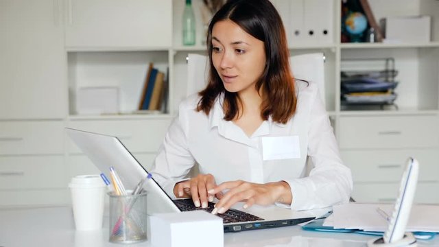 Practicioner girl in medical uniform is working at  laptop  in clinic