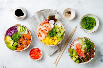 Hawaiian salmon, tuna and shrimp poke bowls with seaweed, avocado, mango, pickled ginger, sesame seeds. Top view, overhead, flat lay