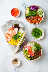 Hawaiian salmon, tuna and shrimp poke bowls with seaweed, avocado, mango, pickled ginger, sesame seeds. Top view, overhead, flat lay