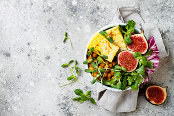 Vegan, detox Buddha bowl recipe with turmeric roasted tofu, figs, chickpeas and greens. Top view, flat lay, copy space