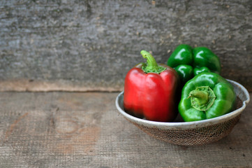 Bell peppers green and red on wooden background in retro sieve. rustic