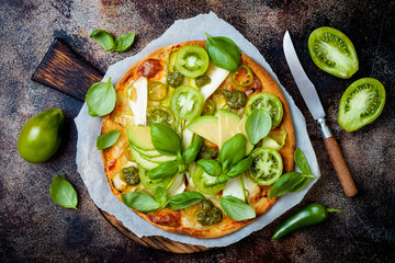 Green pizza with pesto, zucchini, tomatoes, avocado, jalapeno, mozzarella cheese and fresh basil