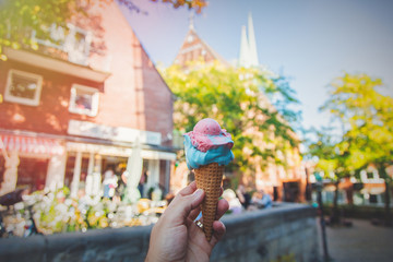 Male hand holding an ice-cream with city street on background. Bremen, Germany
