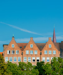 Fototapeta na wymiar View at Catholic church spire and old brick houses in Bremen, Germany