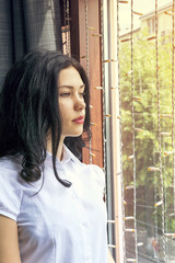 Brooding girl posing inside near window