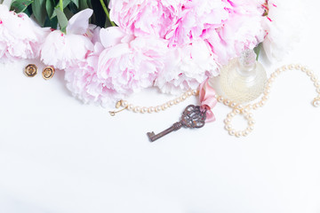 Skeleton key with peony flowers, glamour bottle and jewellery on white leather- romantic love and...