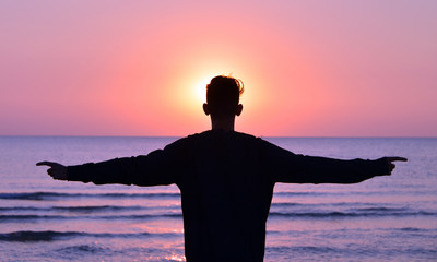 sagome di persone in controluce sulla spiaggia al sorgere del sole