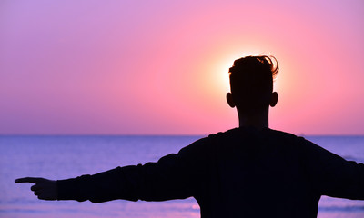 sagome di persone in controluce sulla spiaggia al sorgere del sole