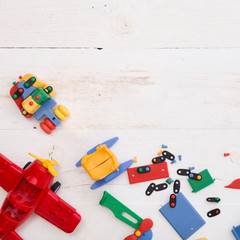 Obraz premium Closeup of multi-color plastic toys and bricks on white wooden background. Early learning and development.