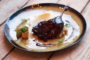 Duck confit with Quinoa puree, celery, apple with cinnamon sauce served on plate. Exclusive restaurant meals