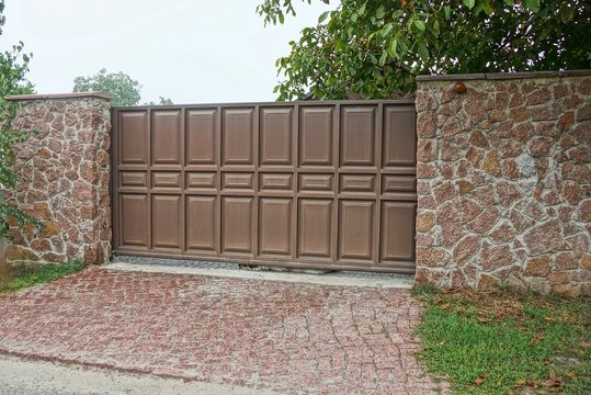 large brown wooden gate and stone fence in the street
