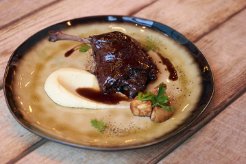 Exclusive restaurant meals served on a table. Duck confit with Quinoa puree, celery, apple with cinnamon sauce served on plate